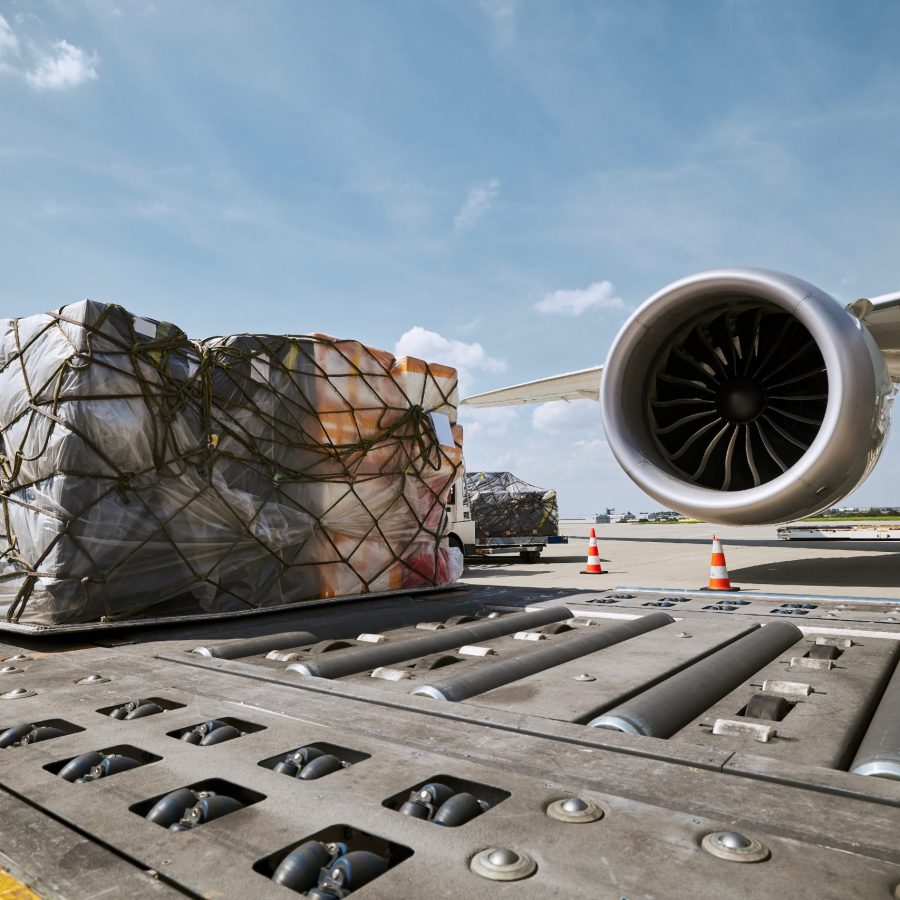 Preparation freight airplane before flight. Loading of cargo containers against jet engine of plane.